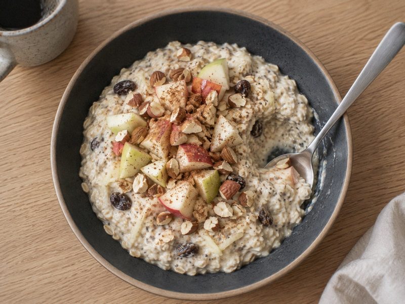 Overnight oats med æble, kanel og skyr på en mørk tallerken, set ovenfra